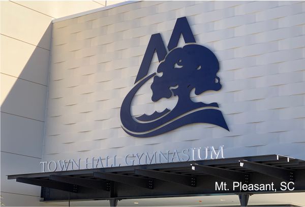 The image shows the exterior facade of a Town Hall or Gymnasium building in Mt. Pleasant, South Carolina. The building features a large logo above the entrance, consisting of stylized mountain peaks and a tree. The text "Mt. Pleasant, SC" is visible in the bottom right corner.