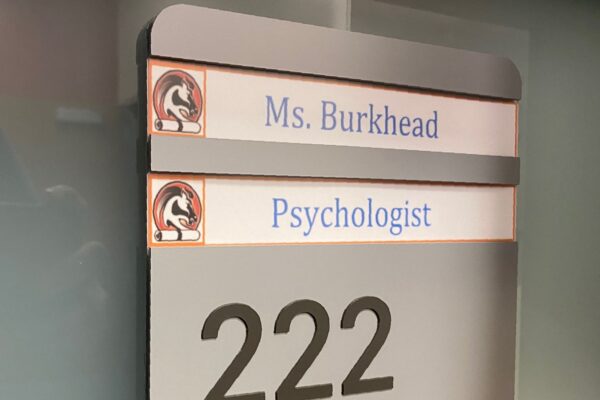 Office sign showing "Ms. Burkhead," "Psychologist," and room number "222" with Braille dots beneath the numerals.